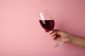 Young girl holding glass of tasty red wine on pink background. Space for text