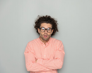astounded curly hair guy with glasses opening mouth while crossing arms