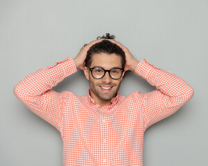 happy casual man with glasses arranging hair and smiling
