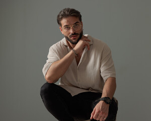 attractive man with glasses crouching with elbows on knees