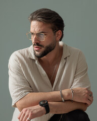 handsome bearded guy with glasses looking to side and crouching
