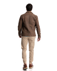 rear view of handsome casual man in brown jacket walking