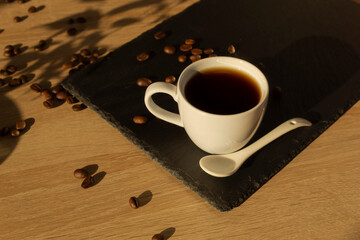 A cup of coffee (espresso) on a dark tray and coffee beans. View from above.