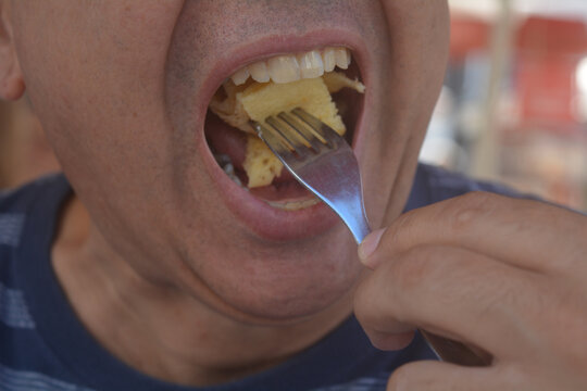 man eating with his mouth open, fork putting food in his mouth