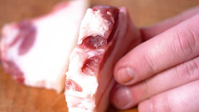 Slicing of salted pork fatback on cutting board, close-up. Ukrainian traditional food - salo	
