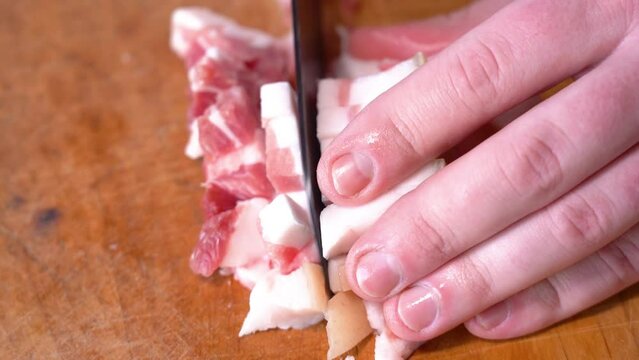 Slicing of salted pork fatback on cutting board, close-up. Ukrainian traditional food - salo	
