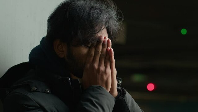 Close up homeless worried anxiety sad stressed Arabian unhappy man in dark city painful head headache injury ill guy bankrupt businessman stress anxious suffer at parking lot depressed Indian male