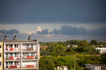 Dramatic colorful sky, before storm and during sunset. Huge clouds formations above residential blocks