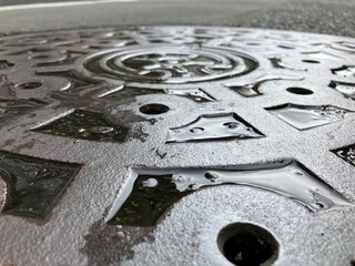 雨に濡れたマンホールの蓋のアップ