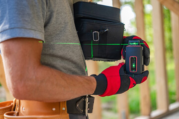 Construction Worker with Modern Laser Leveling Tool in His Hands - obrazy, fototapety, plakaty