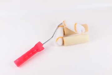 Studio shot against a white background of a clean paint roller with spare rollers under a red handle