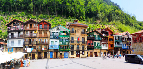 Santiago Plaza is a hidden gem in Pasaia Donibane, Spain, near San Sebastian. Nestled in this charming Basque fishing village, it is a picturesque riverside square lined with colorful buildings - obrazy, fototapety, plakaty