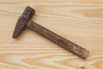 Old hammer with a wooden handle and on a wooden table. Top view, close up. Industrial item for repair.