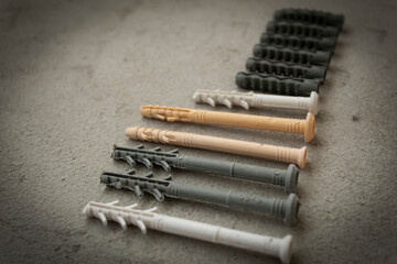 Plastic dowels of various sizes on a concrete surface. Consumables for repairs. Composition in rhythm.