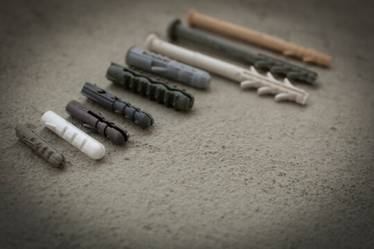 Plastic dowels of various sizes on a concrete surface. Consumables for repairs. Composition in rhythm. Creative image.
