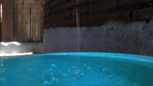 water dripping from the tap, clear stream of water from the tap. against a brick wall background.