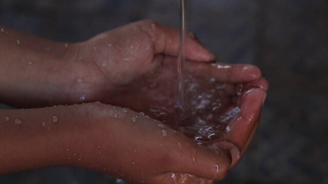 hands holding clean water, water flows into the hands of a little girl. jawa timur indonesia