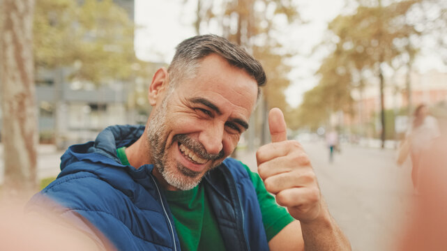 Mature man wearing casual clothes, sitting on bench in the park, talking on video call from smartphone - Powered by Adobe