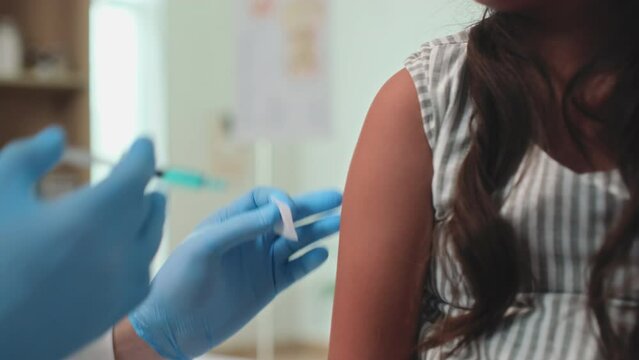 Cropped shot of unrecognizable doctor wiping injection site of girls arm with cotton swab and alcohol before vaccination