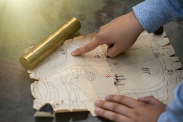 The child's hand points to the place of the buried pirate treasure on the map. A quest for children...