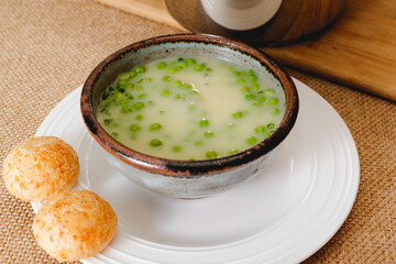 Creamy vegetable soup served with cheese bread. Pureed celery soup with green pea  in a bowl close-up on rustic background