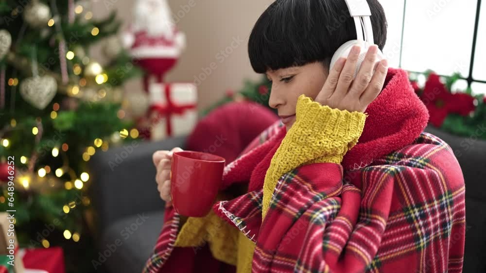 Sticker young chinese woman listening to music drinking coffee by christmas tree at home