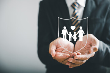 Supporting family futures, Businessman protective gesture complements young family silhouette....