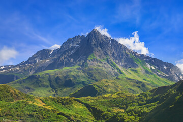 The Caucasus Mountains in Georgia stand tall and proud, their peaks piercing the clear blue sky,...