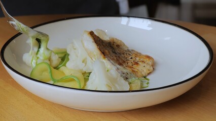The male chef makes the composition of the dish for serving. The cook prepares a dish with fish....