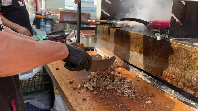 Chef is chopping grilled meat with a knife Turkish Street Food Kokorec made with sheep bowel cooked in wood fired oven.