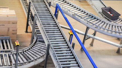 Gray plastic box with items is moved by a conveyor belt on several lines in two levels