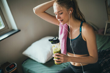 Young athletic and fit woman drinking a healthy smoothie or shake after working out and exercising...