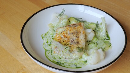 The male chef makes the composition of the dish for serving. The cook prepares a dish with fish. Close-up professional chef in the restaurant kitchen serving a dish adding the last ingredient