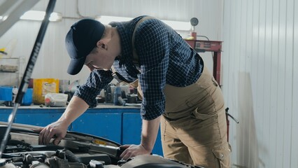 An auto mechanic inspects a car for damage. A mechanic diagnoses a car engine. Old car repair