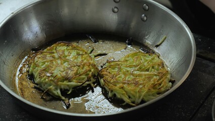 Potato and zucchini pancakes are fried in a pan, frying potato pancakes in oil, pan frying close-up, vegetarian food