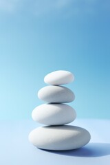Balanced stack of white zen stones, blue background

