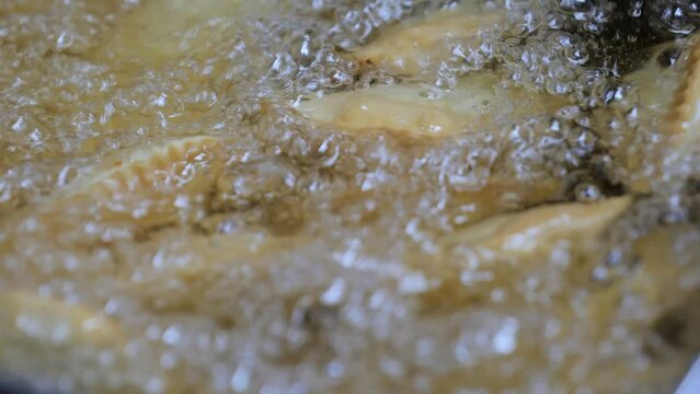 The process of frying chebureks in boiling oil. Pasties with meat fried in sunflower oil, deep-fried. Pie or cheburek is deep-fried.