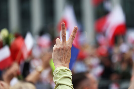 Dłoń człowieka i dwa place tworzą literę V. Wolność.