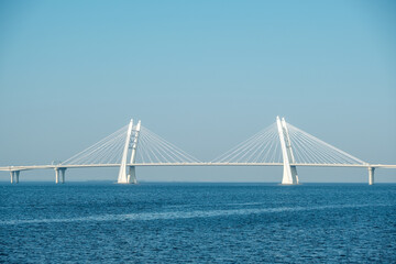 Obraz premium White concrete cable-stayed bridge on supports across the bay.