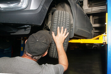  A mechanic inspects the chassis of a car that is raised on a lift.