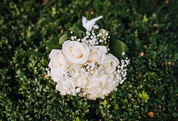 A beautiful wedding bouquet of white roses and wild flowers lies on the green grass. Photography, nature.