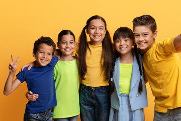 Cheerful cute mutiracial boys and girls taking selfie on yellow