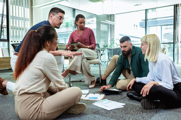 A group of professional people sitting on the floor of the office and working together