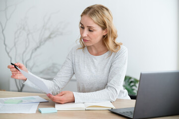 Businesswoman attentively reading documents, work at home office