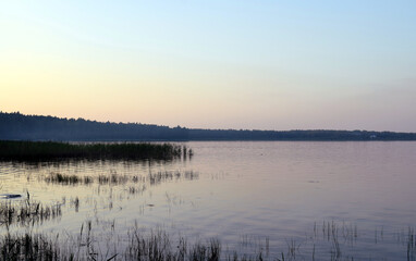 sunset over the lake, forest and trees in the distance.