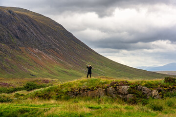 Obraz premium A woman taking pictures of the wonderful mountain scenery of the Glencoe Valley, Scotland.
