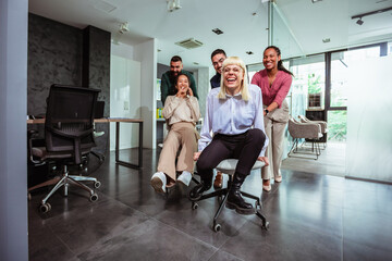 Group of professional people racing with the chairs while on a break in the modern office