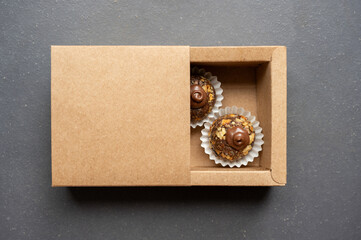 Brazilian chocolate fudge balls with nuts inside the carton box. Traditional Brazilian sweets for parties, grey background, copy space