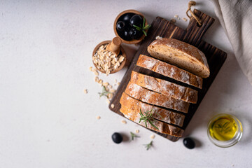 Homemade sourdough ciabatta slice bread with olives and rosemary on a white abstract table. Artisan bread