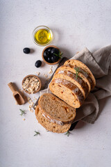 Homemade sourdough ciabatta slice bread with olives and rosemary on a white abstract table. Artisan bread